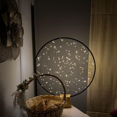 a lamp sitting on a table with a food basket beside it, round loop shape with lots of LEDs inside it.