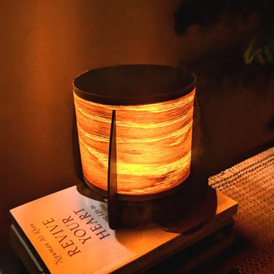 A small compact wood veneer lamp on a sidetable set in a warm cozy tone.