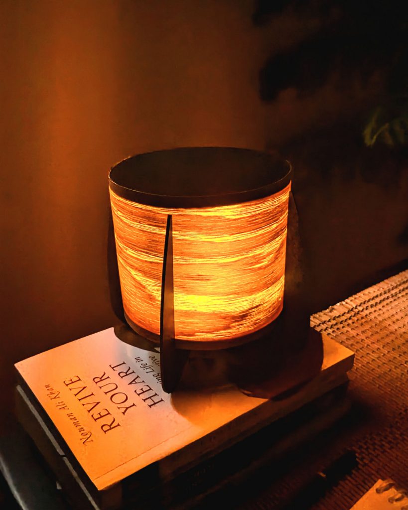 A small compact wood veneer lamp on a sidetable set in a warm cozy tone.